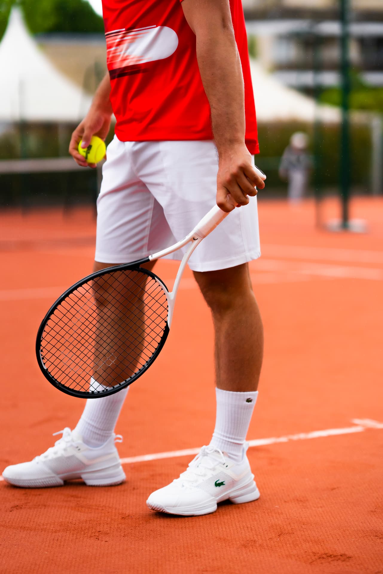 Competitive tennis player preparing with a racket and ball on a clay court