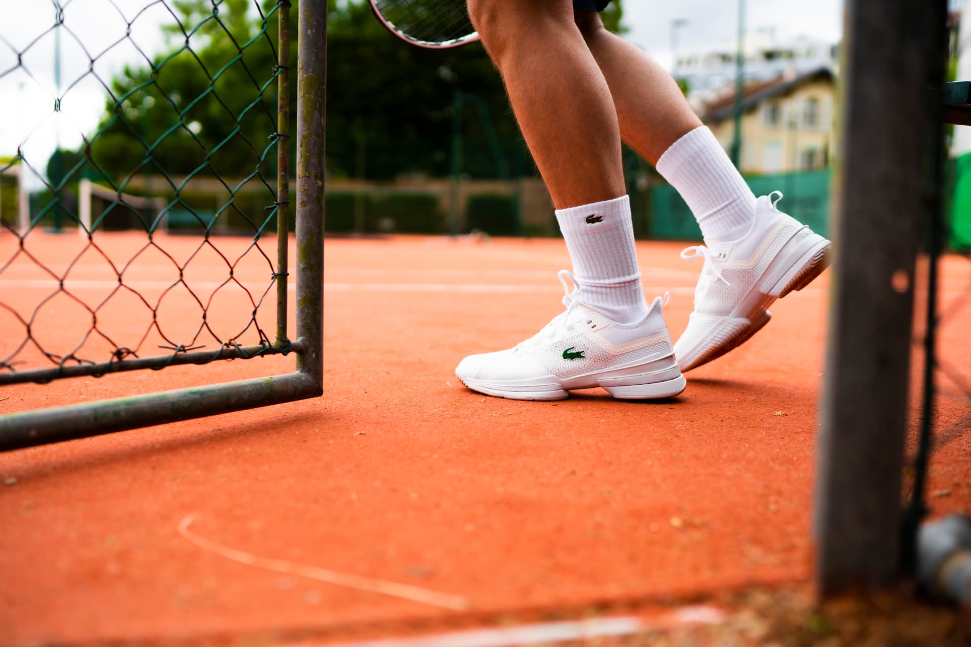 Tennis player entering a clay court through the courtside gate